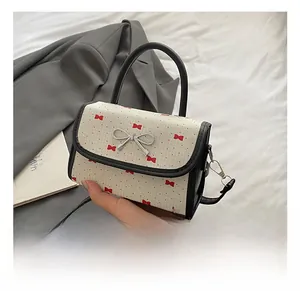 Detail of white embossed leather bag with red bow prints and silver metallic clasp