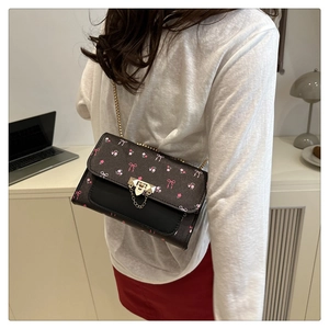 Close-up of vintage mini crossbody bag with pink floral patterns and gold chain strap