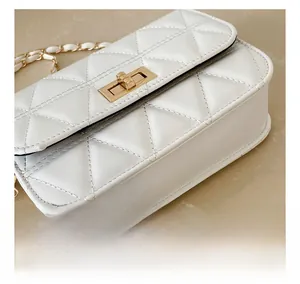 Close-up of white quilted leather bag showing golden twist lock and chain strap detail