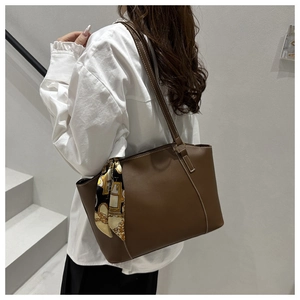 Detail view of brown faux leather tote bag with white stitching and floral scarf handle