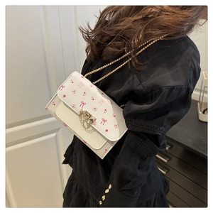 Detailed side view of floral crossbody bag with gold chain and bow patterns