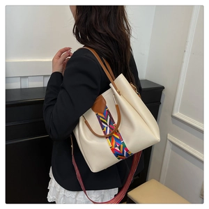 Detail of cream bucket bag with colorful ethnic strap and brown leather handles