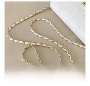 Detail view of the golden metal chain interlaced with white leather on a quilted handbag