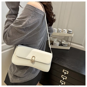 Détail d'un sac baguette blanc minimaliste avec fermoir doré porté par un mannequin