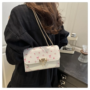 Détail d'un sac blanc à chaîne avec motifs floraux roses et fermoir doré chic