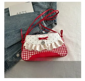 Detail of red gingham shoulder bag with ruffles, bow, and heart pendant on white background