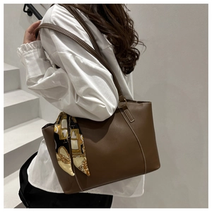 Detail of dark brown tote bag with white contrast stitching and geometric silk scarf decoration