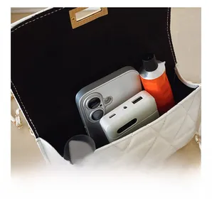 Internal capacity of white quilted chain bag showing phone and cosmetics storage