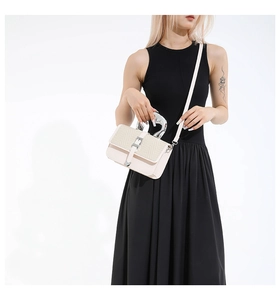 Detail of elegant cream handbag with woven flap and silver circular handle on model