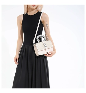 Detail of cream crossbody bag featuring V-shaped woven texture and unique silver metal handle