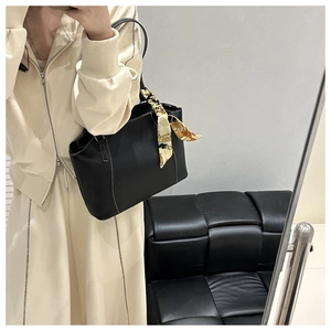 Detail of vintage soft leather tote bag with white stitching and printed silk scarf