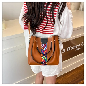 Brown leather tote with colorful geometric woven straps and circular handle on model