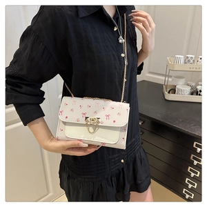 Detail of floral crossbody bag with pink bow prints and gold chain strap on shoulder