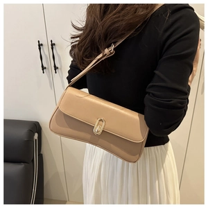 Modèle portant un sac sous le bras beige chic avec fermoir doré et fine bandoulière