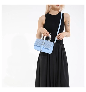 Detail of light blue crossbody bag with silver metal handle and V-pattern weaving texture