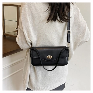 Classic black rectangular shoulder bag with elegant gold twist lock worn by a model