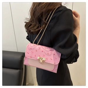 Detail of pink cherry and bow print handbag with gold chain strap and metal clasp