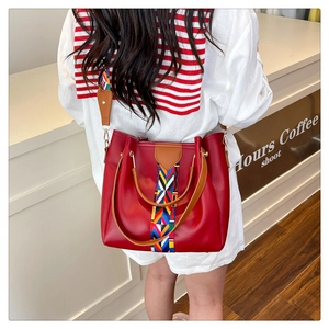 Detail of red leather tote bag featuring bohemian woven strap and decorative front band