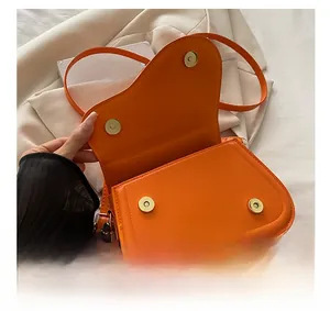 Detail view of the bright orange saddle bag with gold magnetic buckle closures