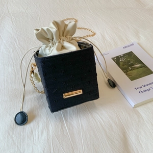 Dettaglio della borsa a secchiello in tweed nero con fodera e catena dorata elegante