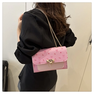 Pink chain strap shoulder bag with cherry patterns and metal lock shown on a model