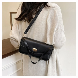 Classic black leather crossbody bag with gold lock and wide shoulder strap on model