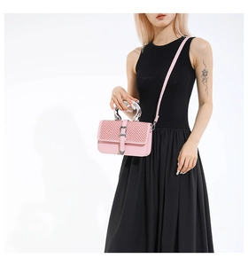 Detailed view of pink woven leather handbag with silver heart buckle and metal handle