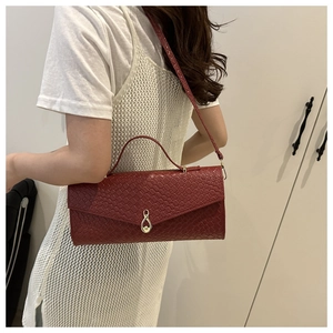 Dettaglio borsa rosso scuro in pelle intrecciata con chiusura dorata a infinito