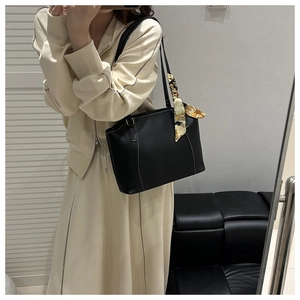 Detail of black faux leather tote with white contrast stitching and yellow silk scarf