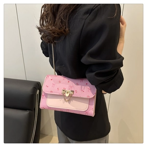 Détail du sac à bandoulière en cuir rose avec motifs cerise et chaîne dorée