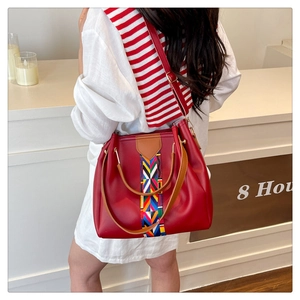 Detailed close-up of a red leather bucket bag featuring a colorful geometric woven strap