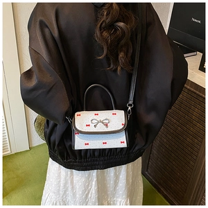 Detail of white PU shoulder bag featuring red bow prints and silver metallic buckle