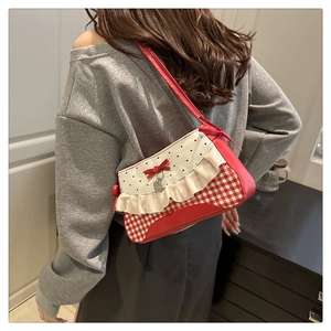 Detail of red and white checkered baguette bag with lace trim and bow on model shoulder