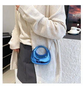 Close-up of bright blue metallic acrylic crescent bag with gold chain strap on a model