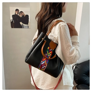 Detail of black leather tote bag with colorful ethnic geometric woven straps and handles