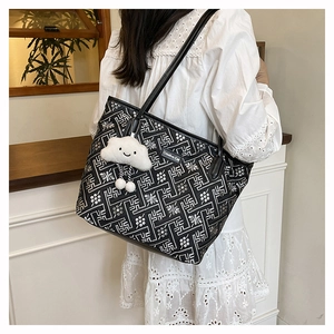 Detail of a black and white geometric tote bag with a plush cloud charm and long handles