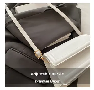 Detail showing the adjustable gold buckle and smooth leather texture on white crossbody bag