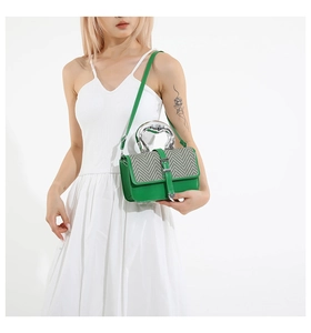Detail of green leather square bag with silver metal handle and herringbone pattern texture