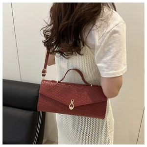 Dettaglio della borsa bordeaux intrecciata con chiusura a goccia dorata e texture pelle
