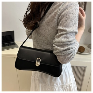 Detail of classic black leather shoulder bag with gold oval twist lock shown on model
