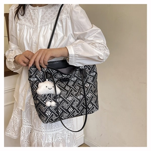 Detail of a black floral tote bag with a white cloud plush charm and shoulder straps