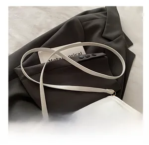 Close-up of minimalist white leather crossbody bag with comfortable strap and golden buckle
