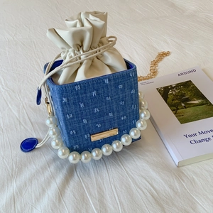 Dettaglio della borsa a secchiello in denim con manico di perle e sacchetto interno beige