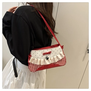 Detail of red checkered fabric bag with heart pendant and white ruffle trim details