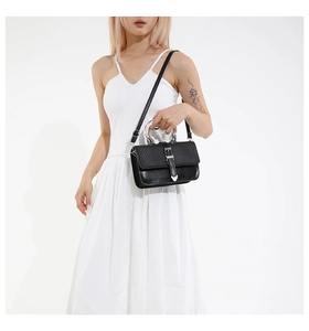 Detail of black woven texture handbag with silver metal handle and heart buckle