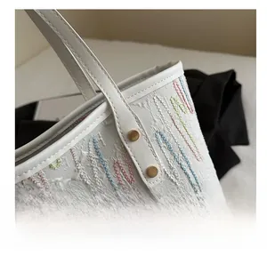 Detail of woven tote bag featuring colorful wavy embroidery and gold rivet accents