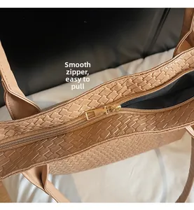 Detail view of smooth golden metal zipper closure on a beige woven texture tote bag