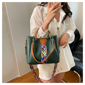 Detail of green leather handbag with colorful woven pattern and wide printed strap