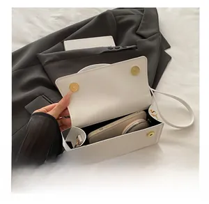 Internal view of a white leather square bag showing its spacious capacity and magnetic closure