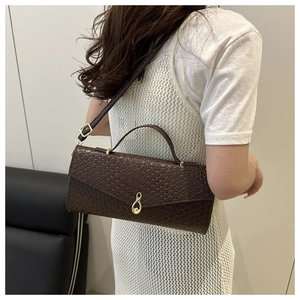 Detail view of deep brown woven texture handbag with elegant gold buckle on a model